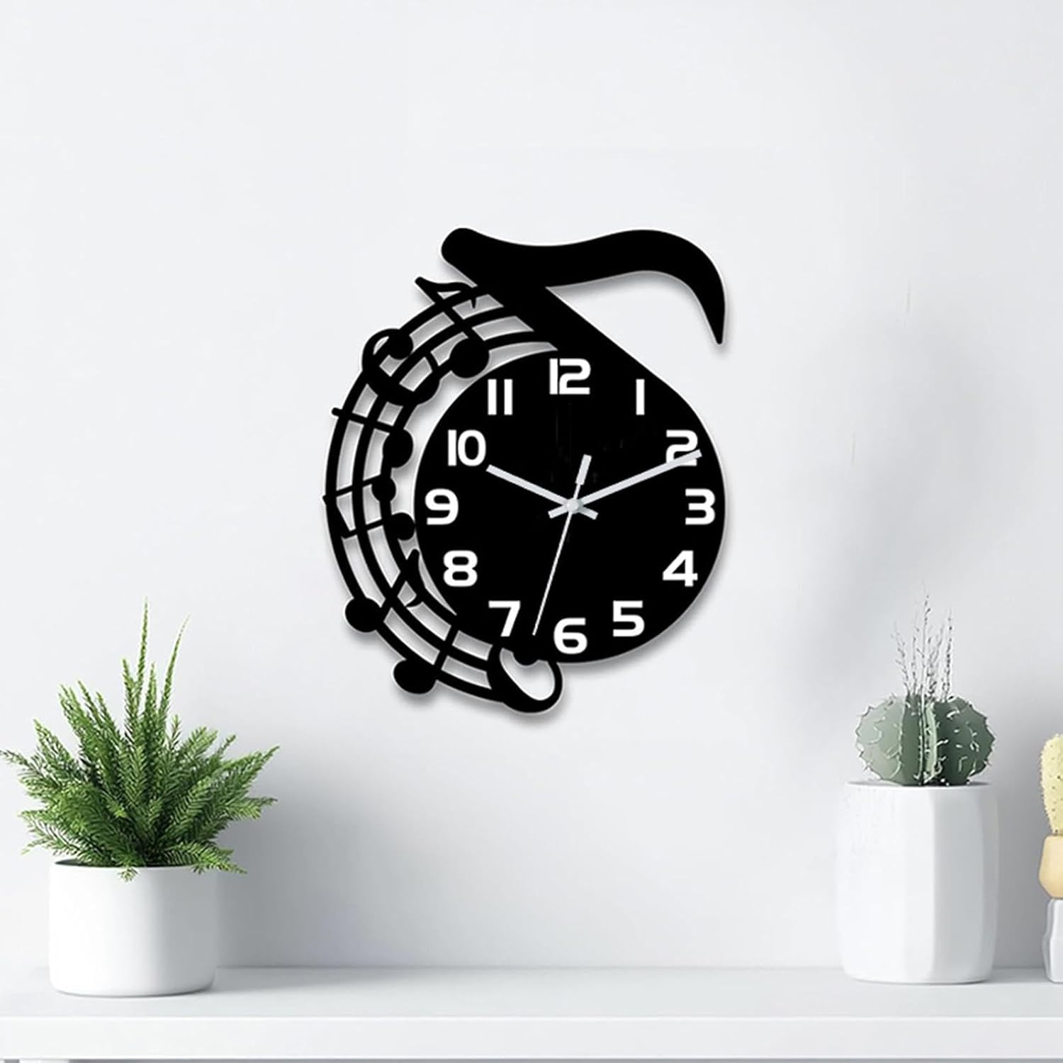Eine schwarze Wanduhr im Musiknoten-Design hängt an einer weißen Wand, flankiert von zwei Topfpflanzen auf einem Regal.