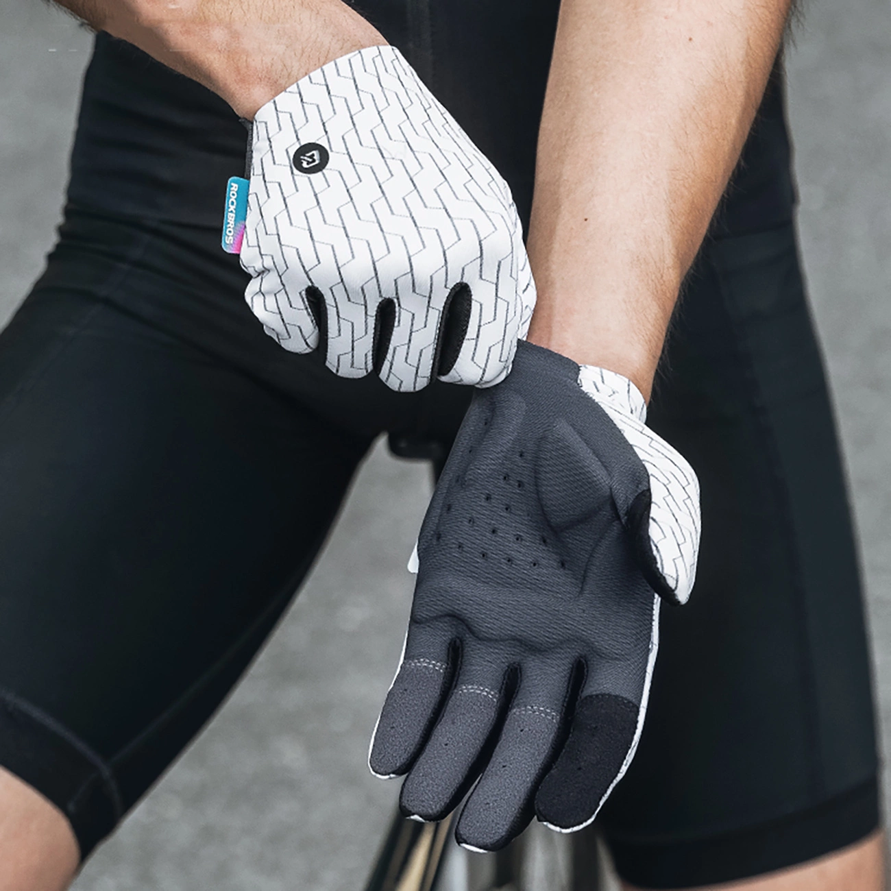 Ciclista che indossa guanti da ciclismo con motivo bianco e nero.