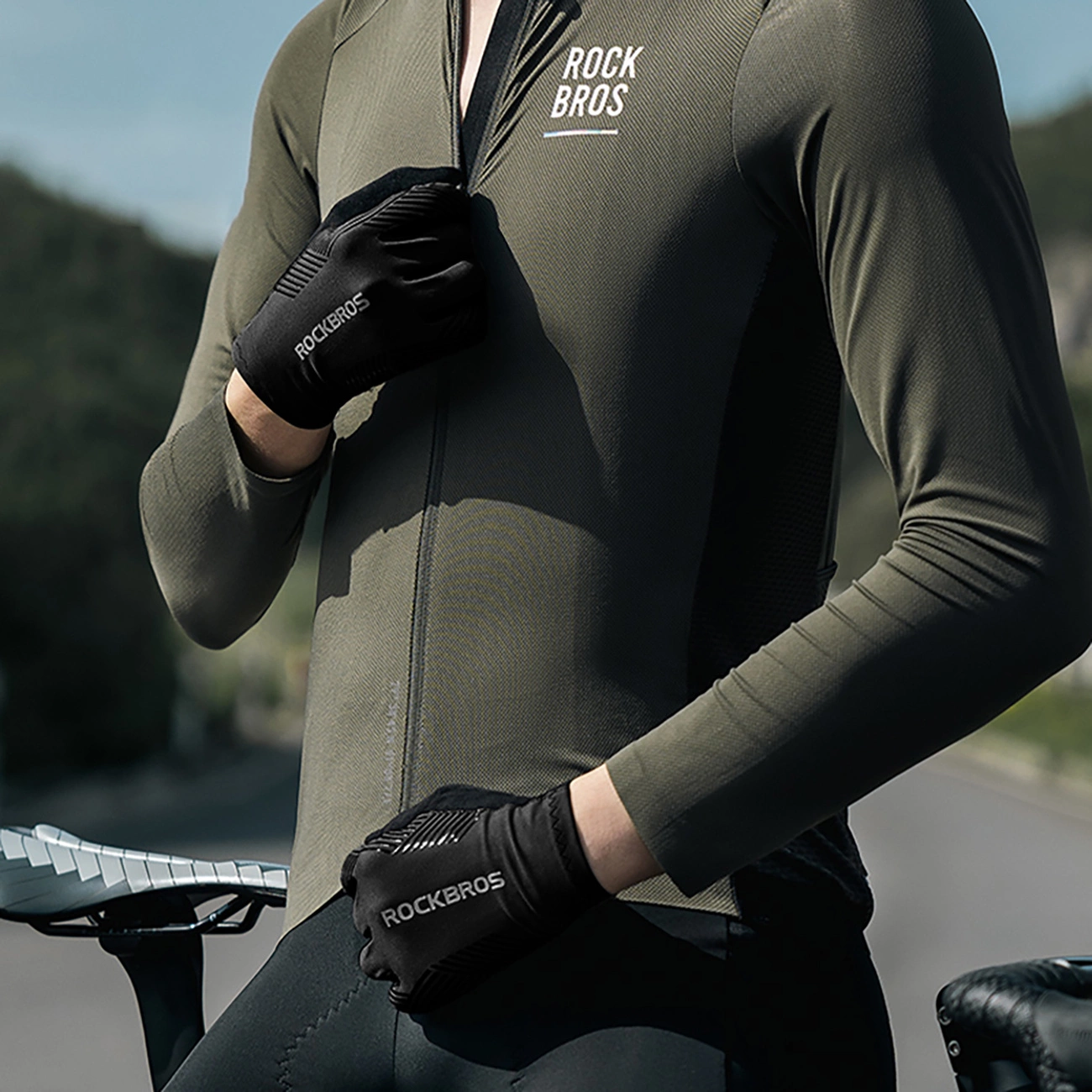 Un ciclista con maglia verde e guanti neri regola la cerniera, all'aperto vicino a una bicicletta.