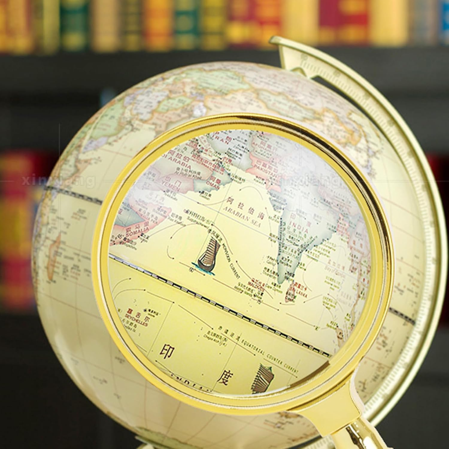 Ein goldener Globus mit einer integrierten Lupe zeigt die arabische Halbinsel und Indien.