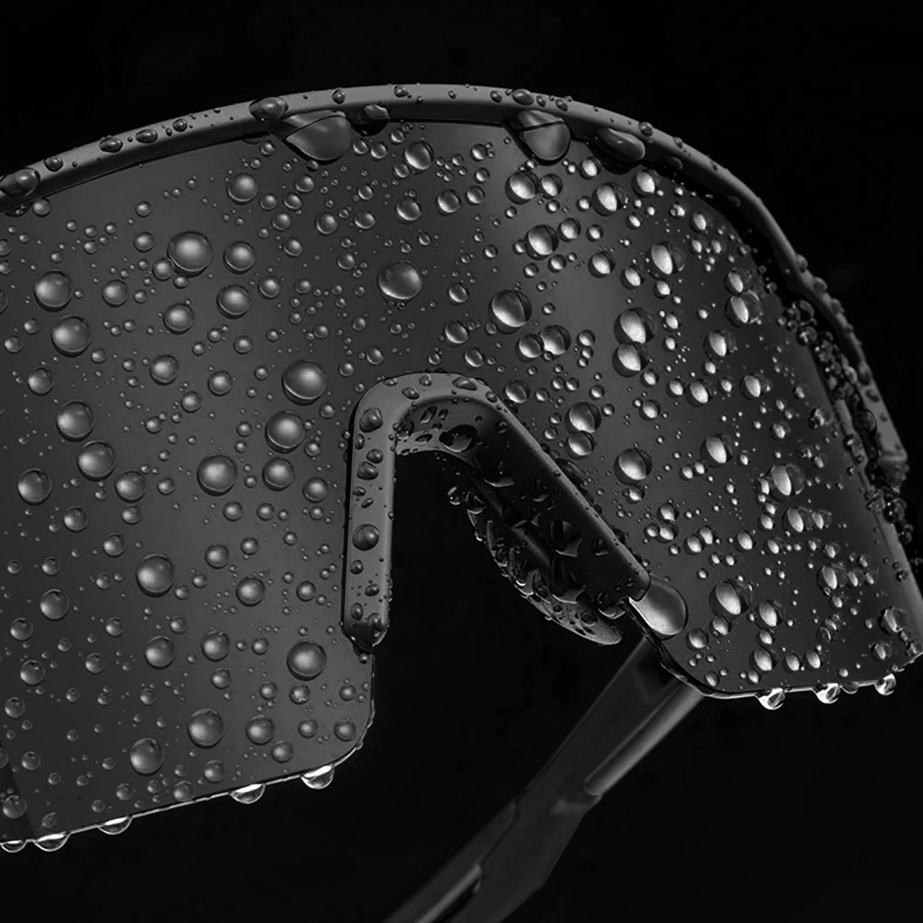 Gocce d'acqua coprono la superficie liscia di occhiali da sole sportivi neri su sfondo scuro.