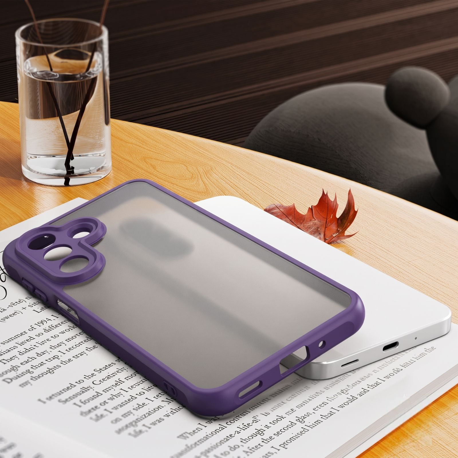 Eine lila Smartphone-Hülle liegt auf einem Buch, daneben ein Glas Wasser auf einem Holztisch.