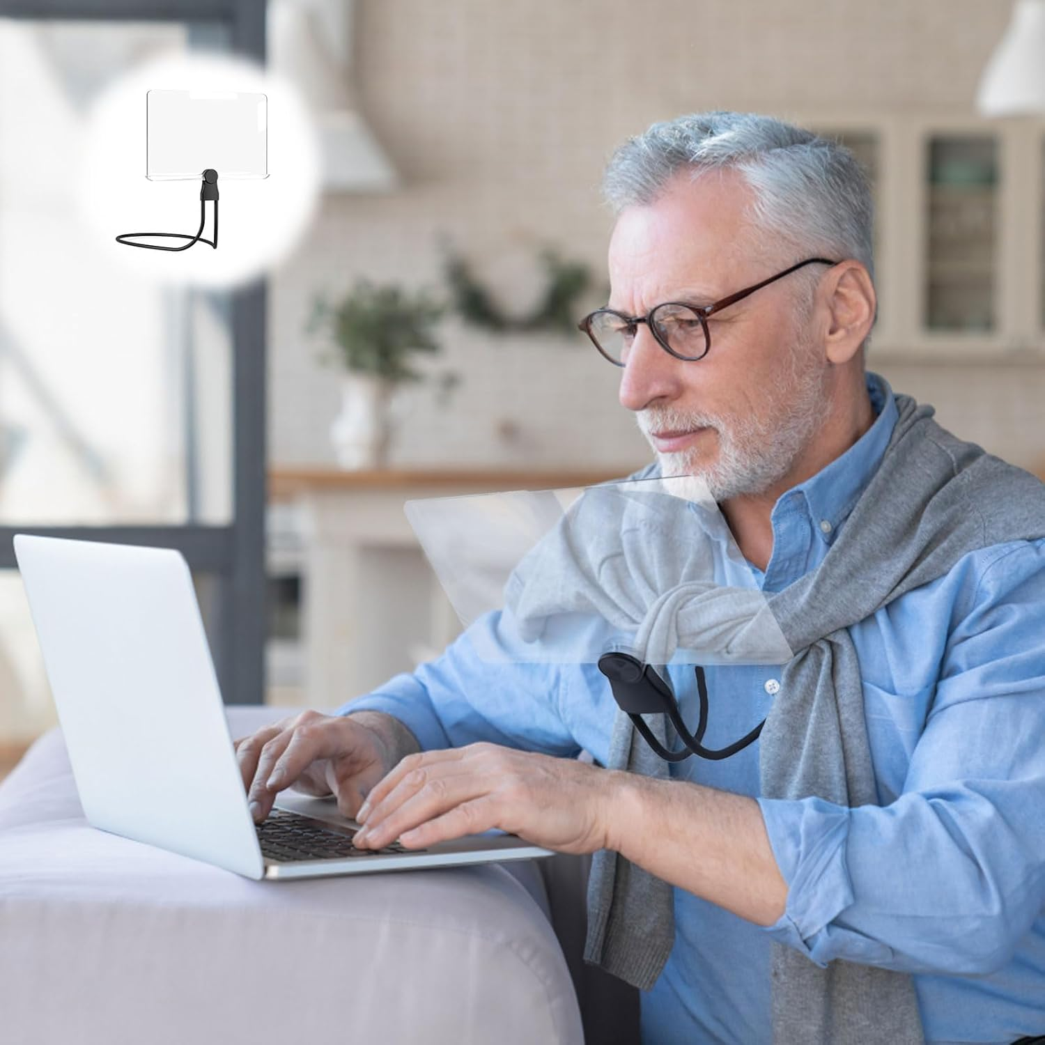 Älterer Mann nutzt einen Laptop und trägt ein Halsband mit einer Acrylplatte.