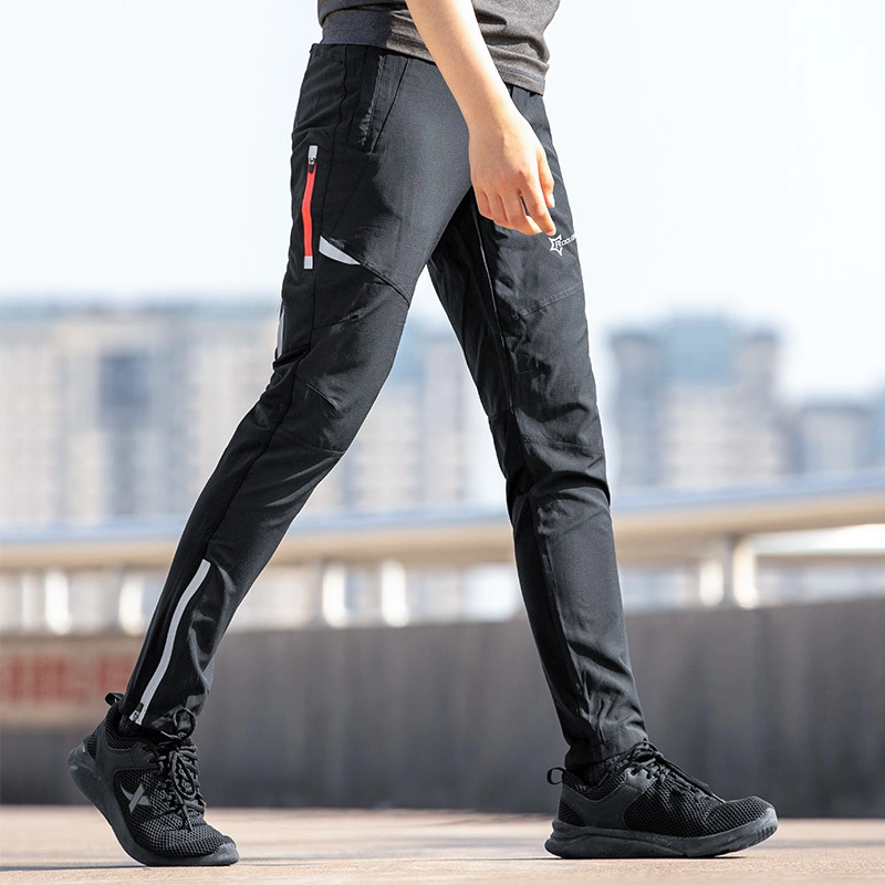 Persona con pantaloni neri da esterno e scarpe da ginnastica che cammina all'aperto.