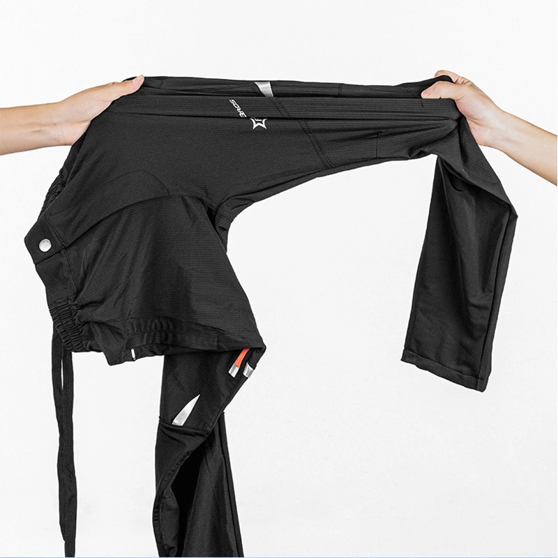 Due mani allungano dei pantaloni neri su uno sfondo bianco.