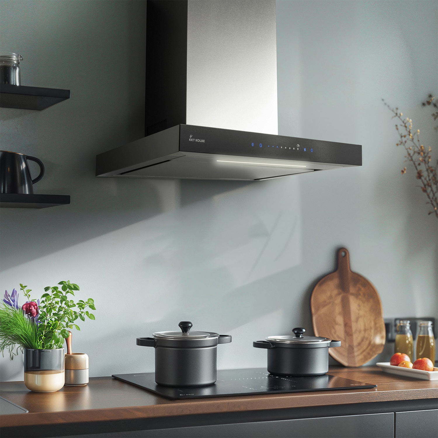 Moderna cappa da cucina sopra un piano cottura con pentole, erbe e un tagliere.