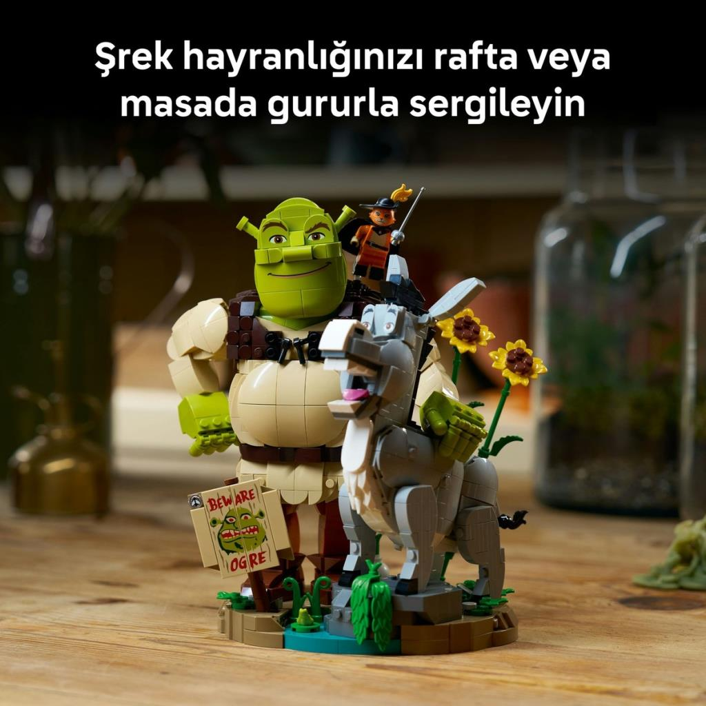 Ahşap bir masa üzerinde sergilenen Shrek, Eşek ve Çizmeli Kedi Lego figürleri.