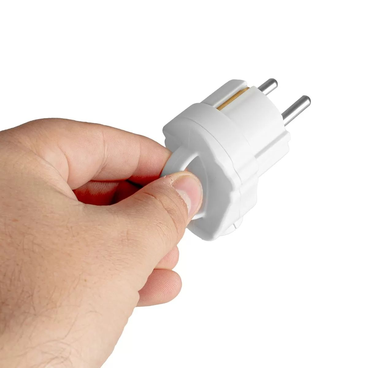 Egy kéz fehér, kétágú elektromos dugót tart fehér háttér előtt.