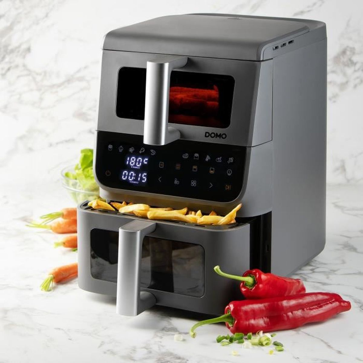 Une friteuse à air grise à double bac avec des frites sur un plan de travail en marbre.