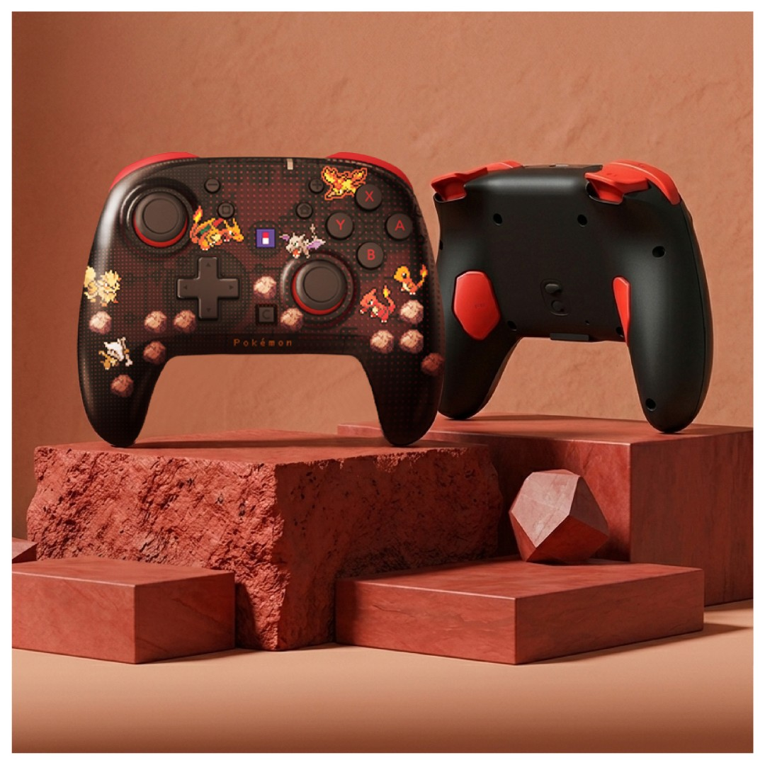 Zwei schwarz-rote Pokemon-Controller auf roten Steinsockeln vor einer Terrakottwand.