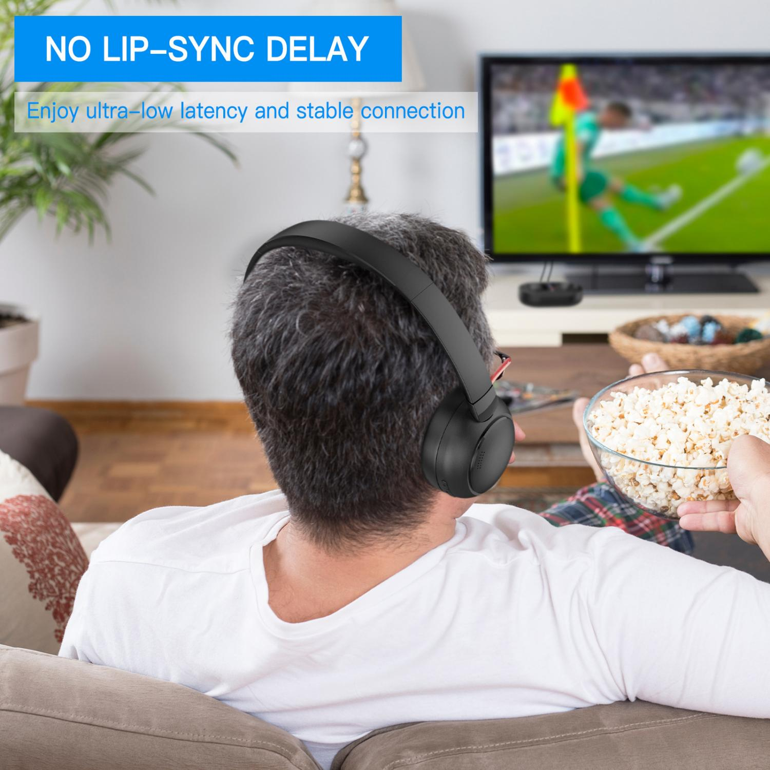 Ein Mann mit schwarzen Kopfhörern sitzt auf einem Sofa, hält Popcorn und schaut Fußball im TV.