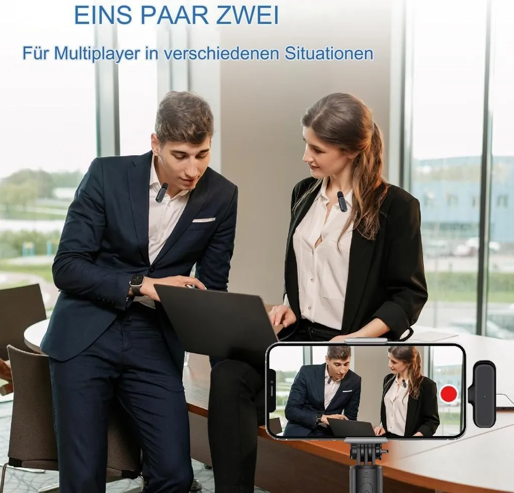 Ein Mann und eine Frau in Geschäftskleidung betrachten in einem Büro einen Laptop, während ein Smartphone auf einem Stativ sie aufnimmt.