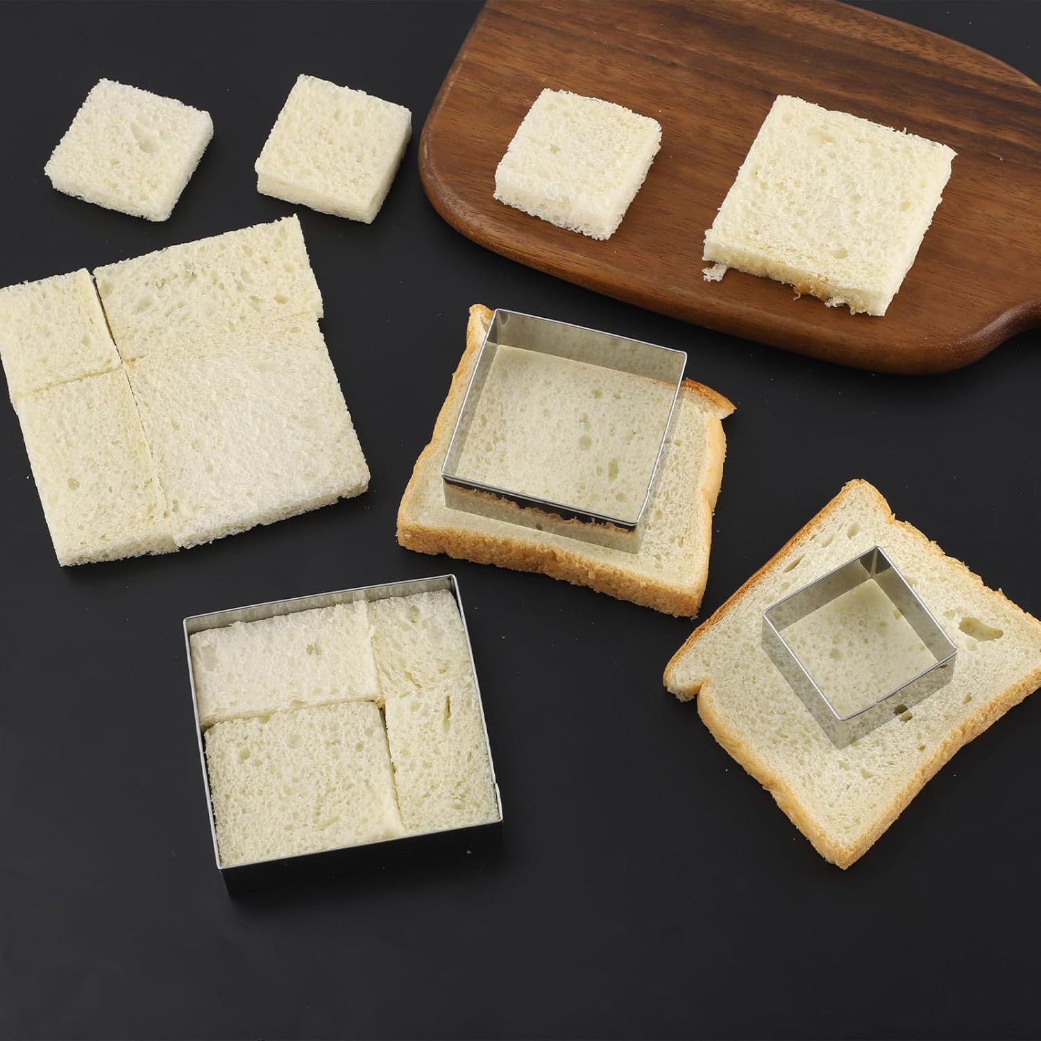 Quadratische Brotscheiben werden mit Metallformen auf einem Holzedelbrett und schwarzem Tisch zugeschnitten.