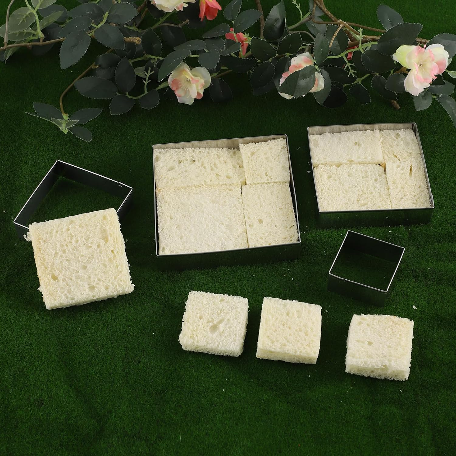 Quadratische Brotscheiben und eckige Metallformen auf grünem Hintergrund, dekoriert mit Blumenranken.