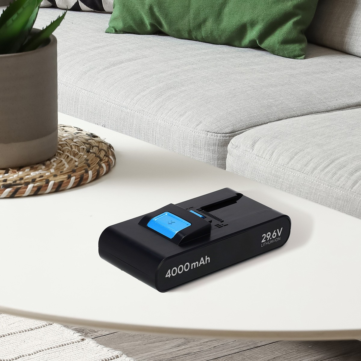 Czarna bateria litowo-jonowa 4000 mAh, 29,6 V na białym stoliku kawowym przed szarą sofą.