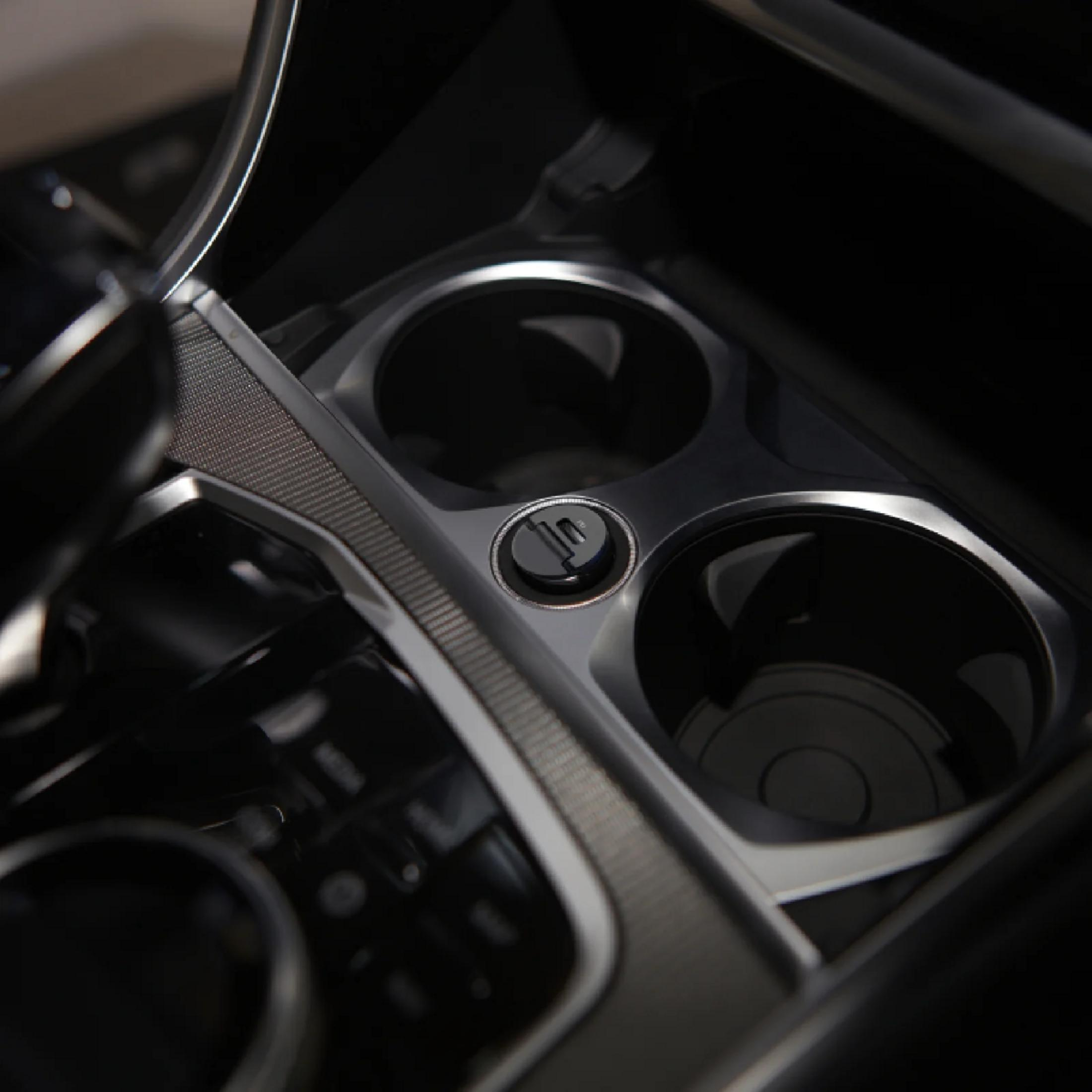 Primo piano della console centrale di un'auto con due portabicchieri e una presa.