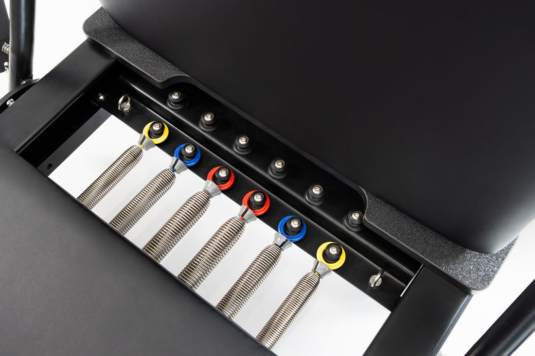 Primer plano de una máquina de pilates reformer con resortes de colores.