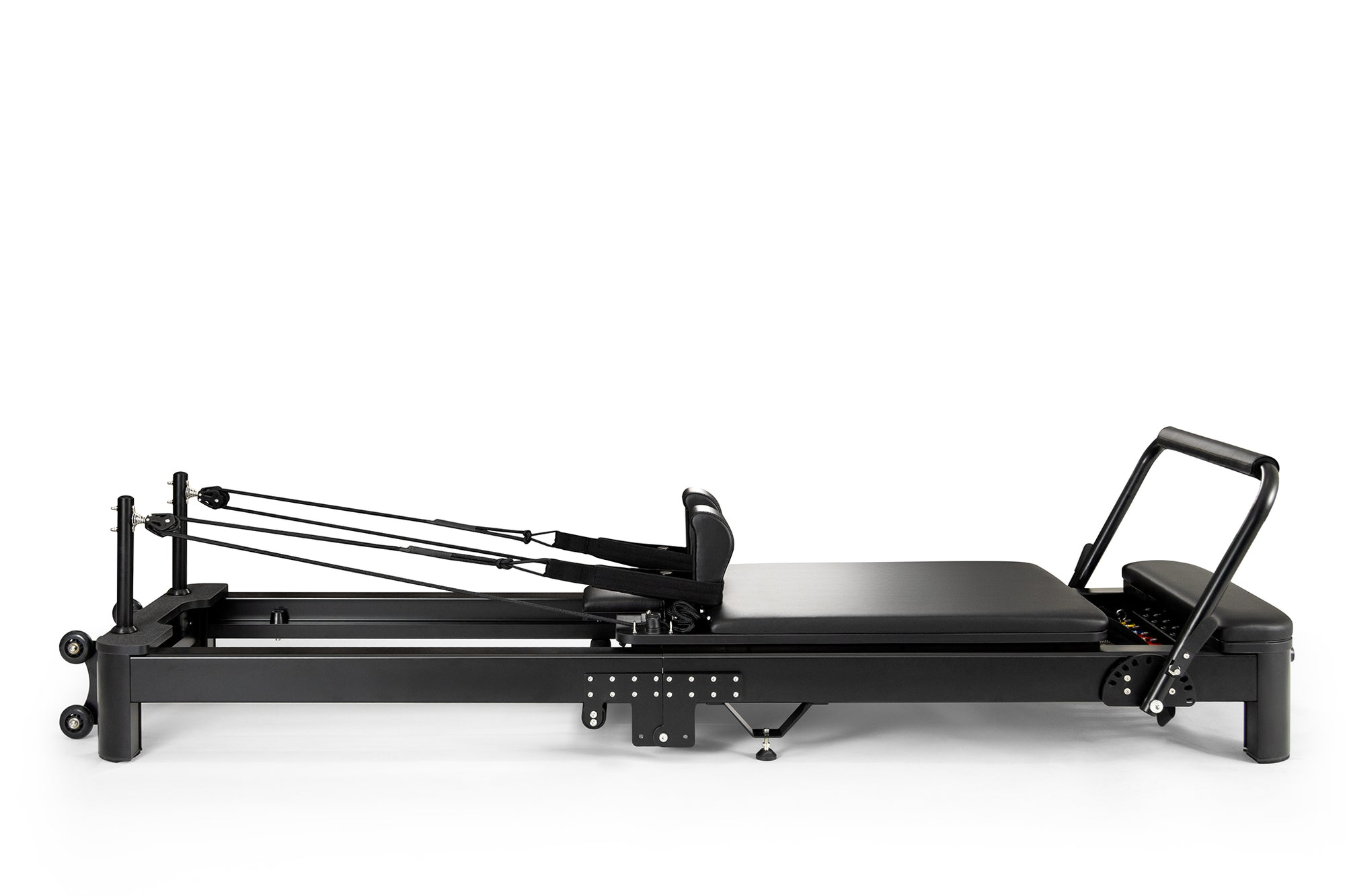 Una máquina reformer de pilates negra con correas y marco ajustable sobre un fondo blanco.