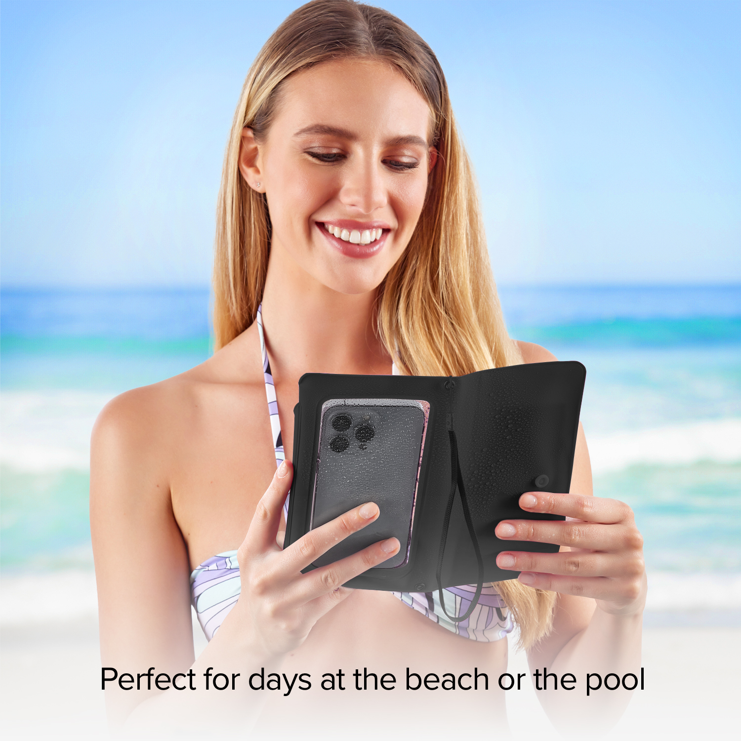 Una mujer rubia en la playa sostiene un teléfono en una funda negra.