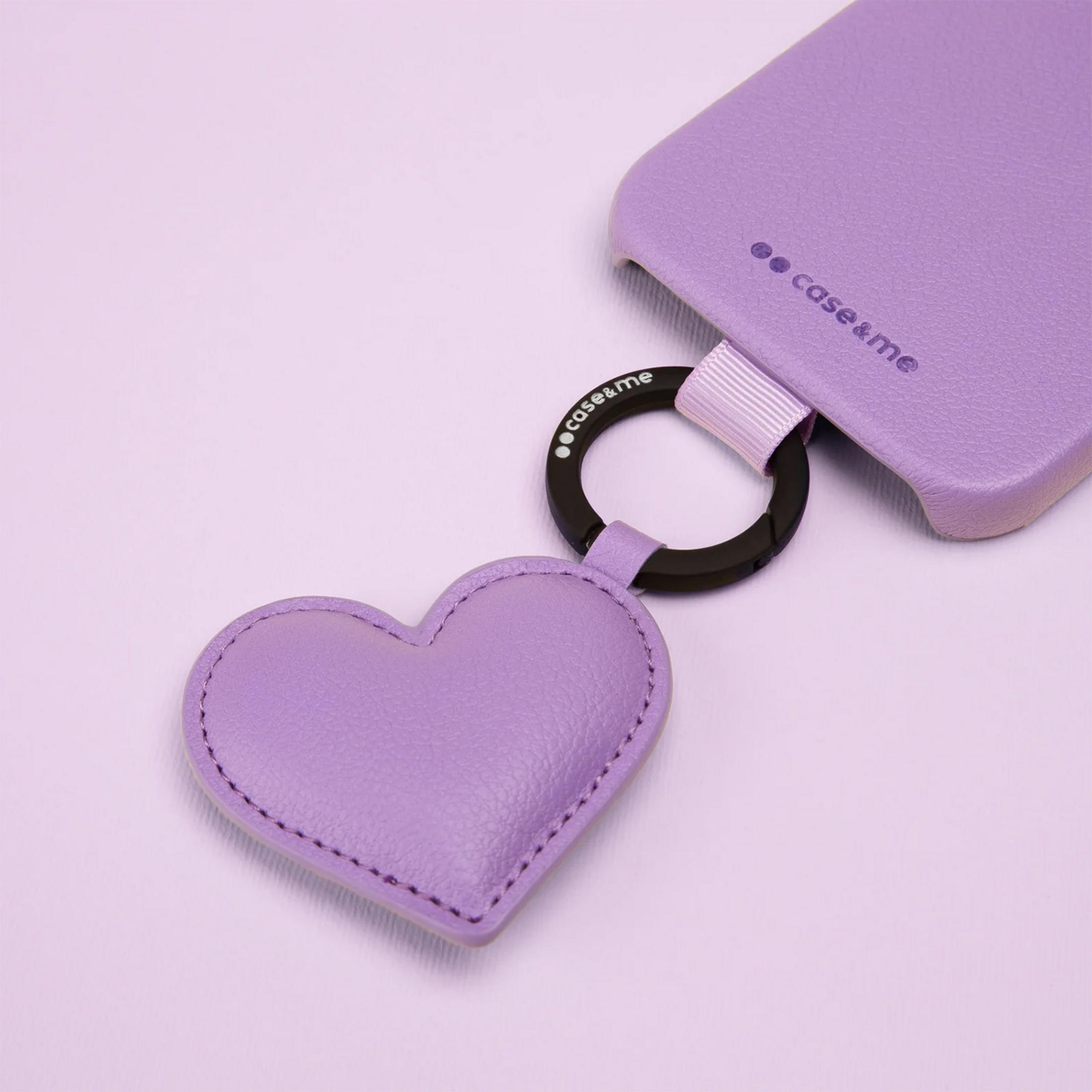 Funda de móvil morada con un colgante de corazón morado a juego sobre fondo morado.