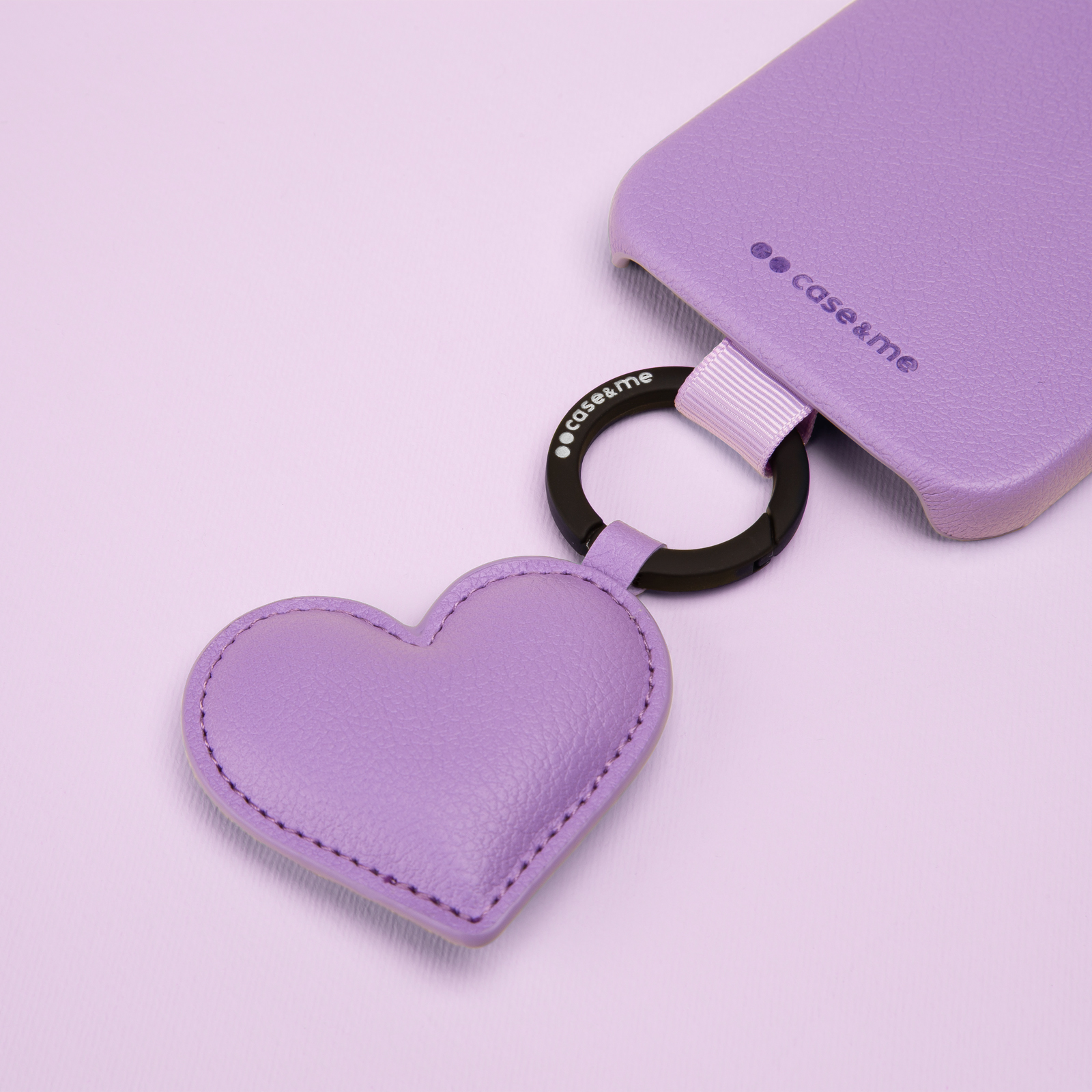 Una funda de móvil morada con un llavero de corazón a juego sobre fondo lila.