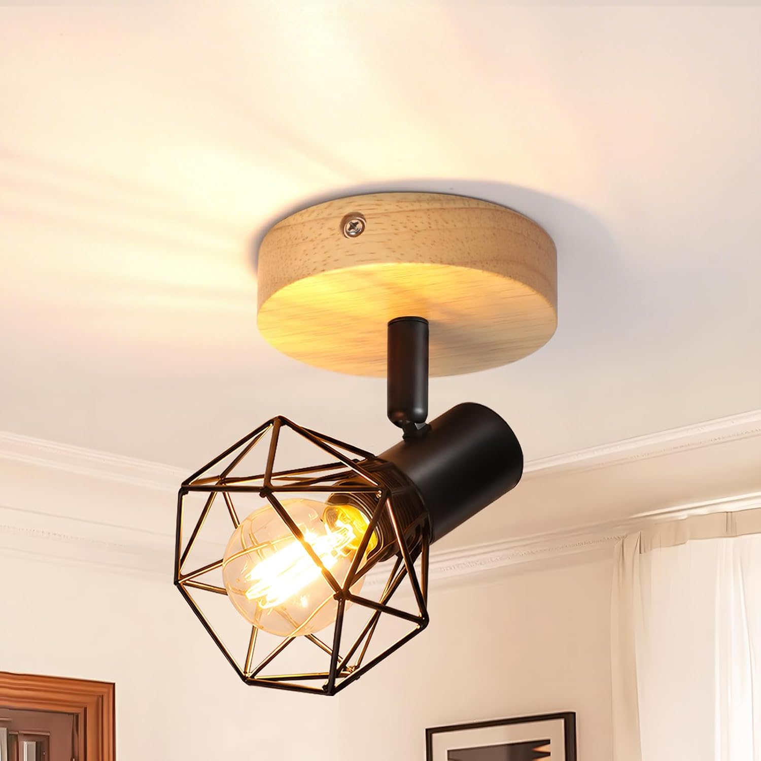 Un foco de techo moderno con jaula de metal negro y base de madera en un techo blanco, emitiendo un brillo cálido.