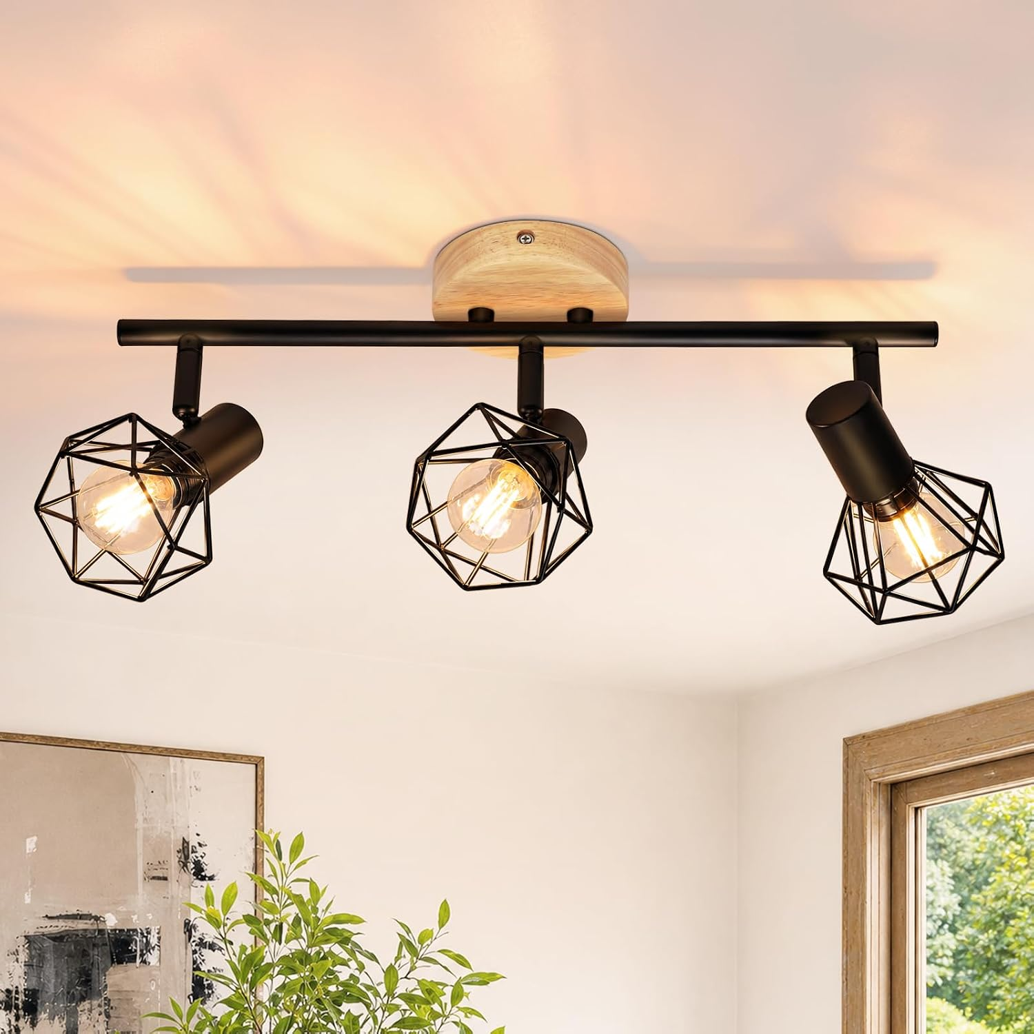 Una lámpara de techo moderna con tres focos de jaula de metal negro en una barra de madera y negro.
