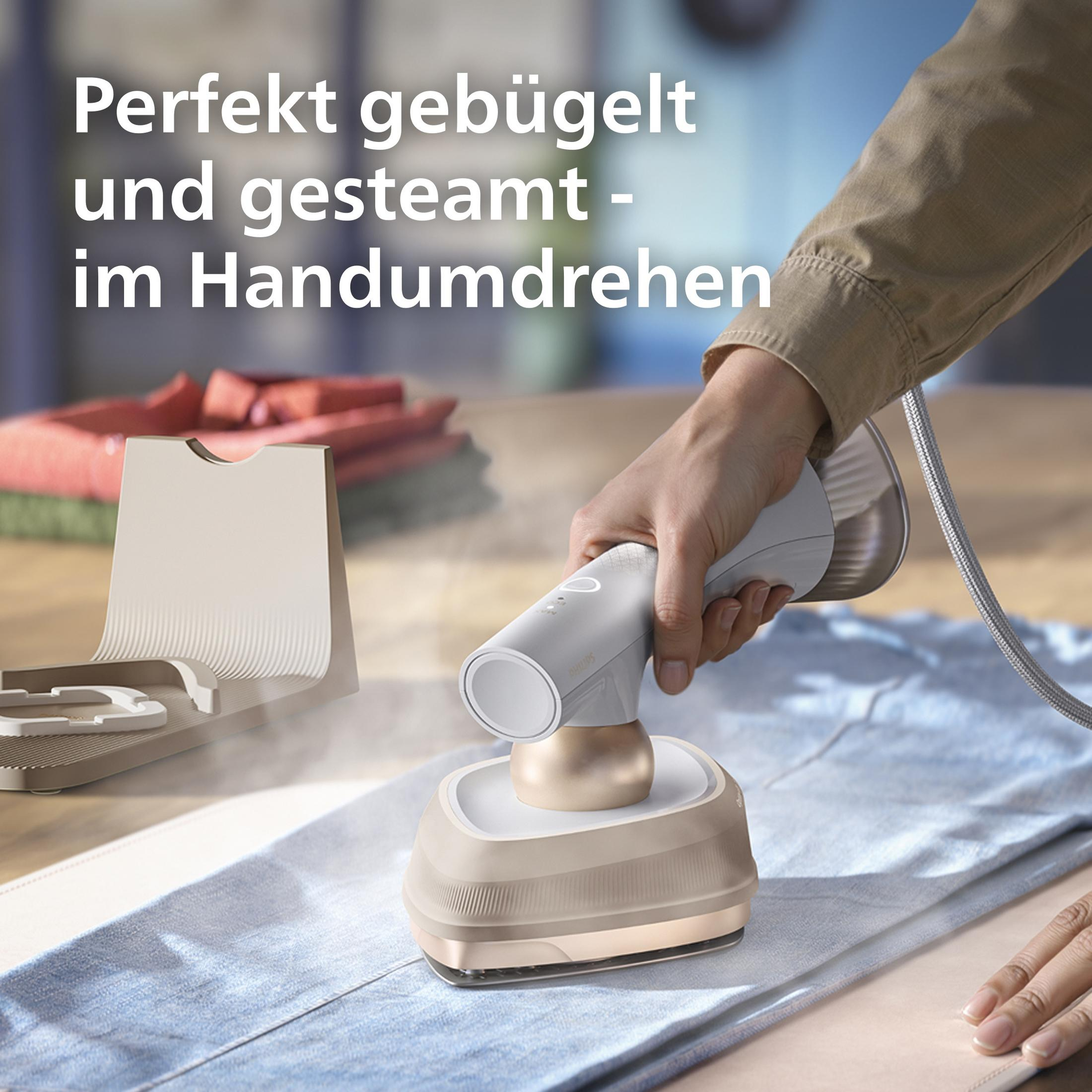 Una mano usa un vaporizzatore per abiti bianco e oro su vestiti blu.