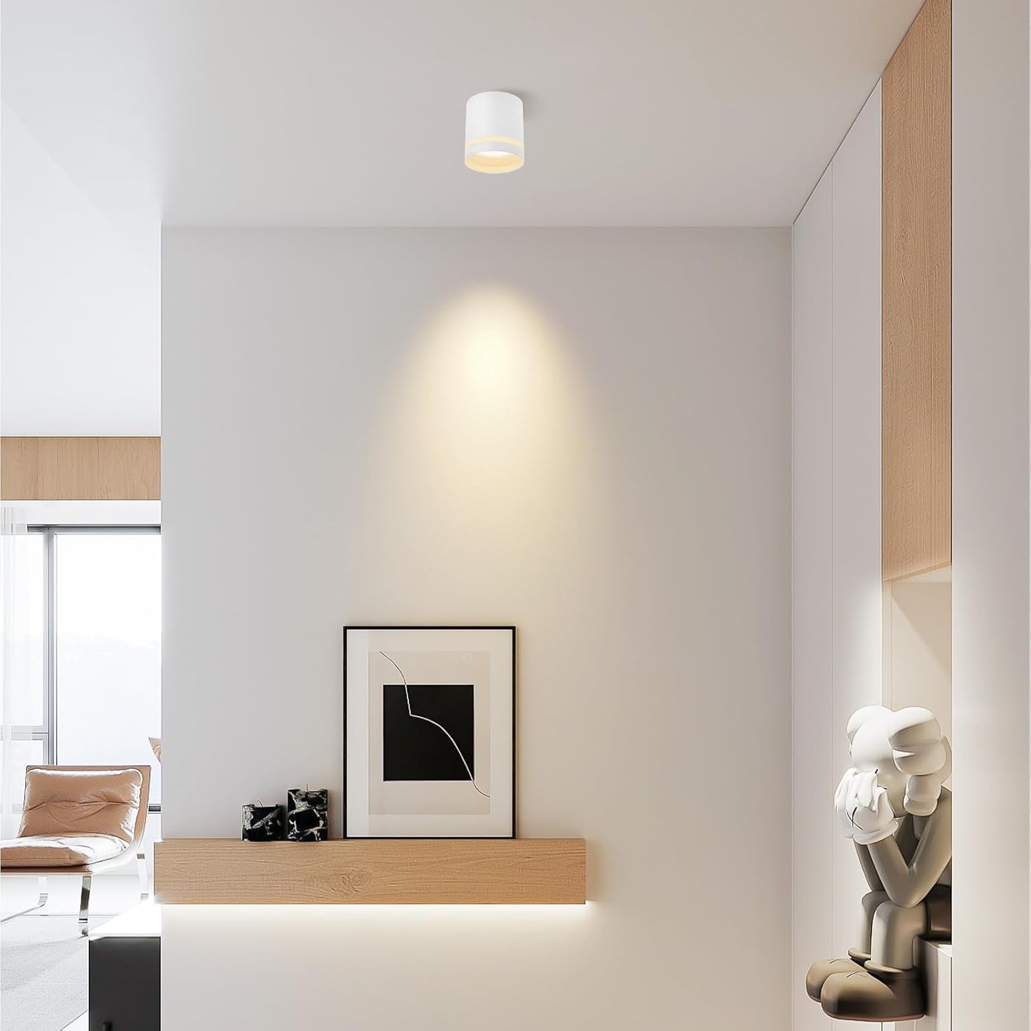Una habitación blanca minimalista con foco de techo, estante flotante de madera con arte abstracto y una figura.