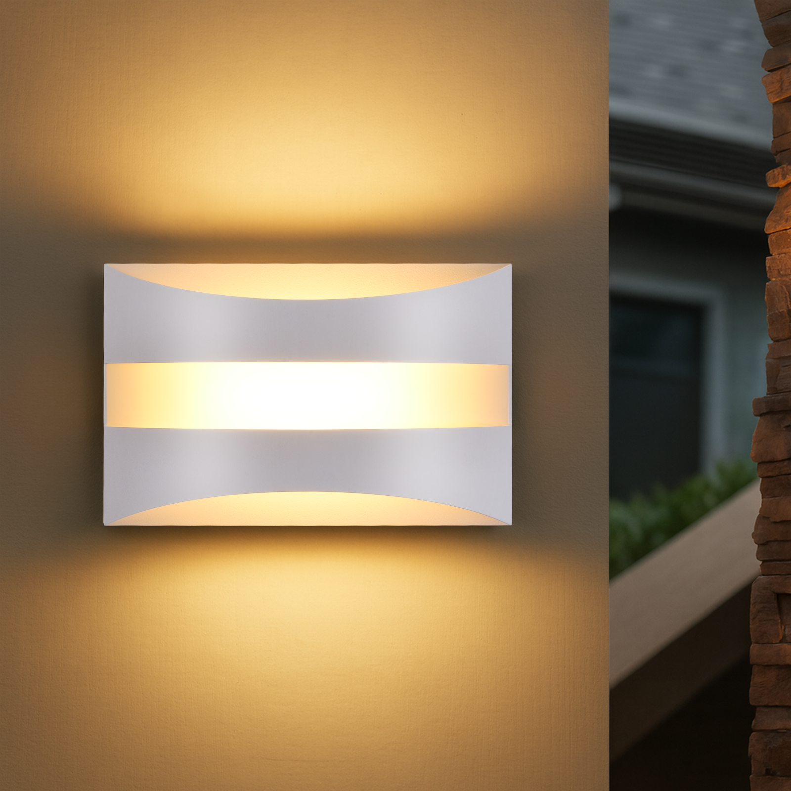 Lámpara de pared exterior blanca y moderna emite luz cálida sobre una pared beige.