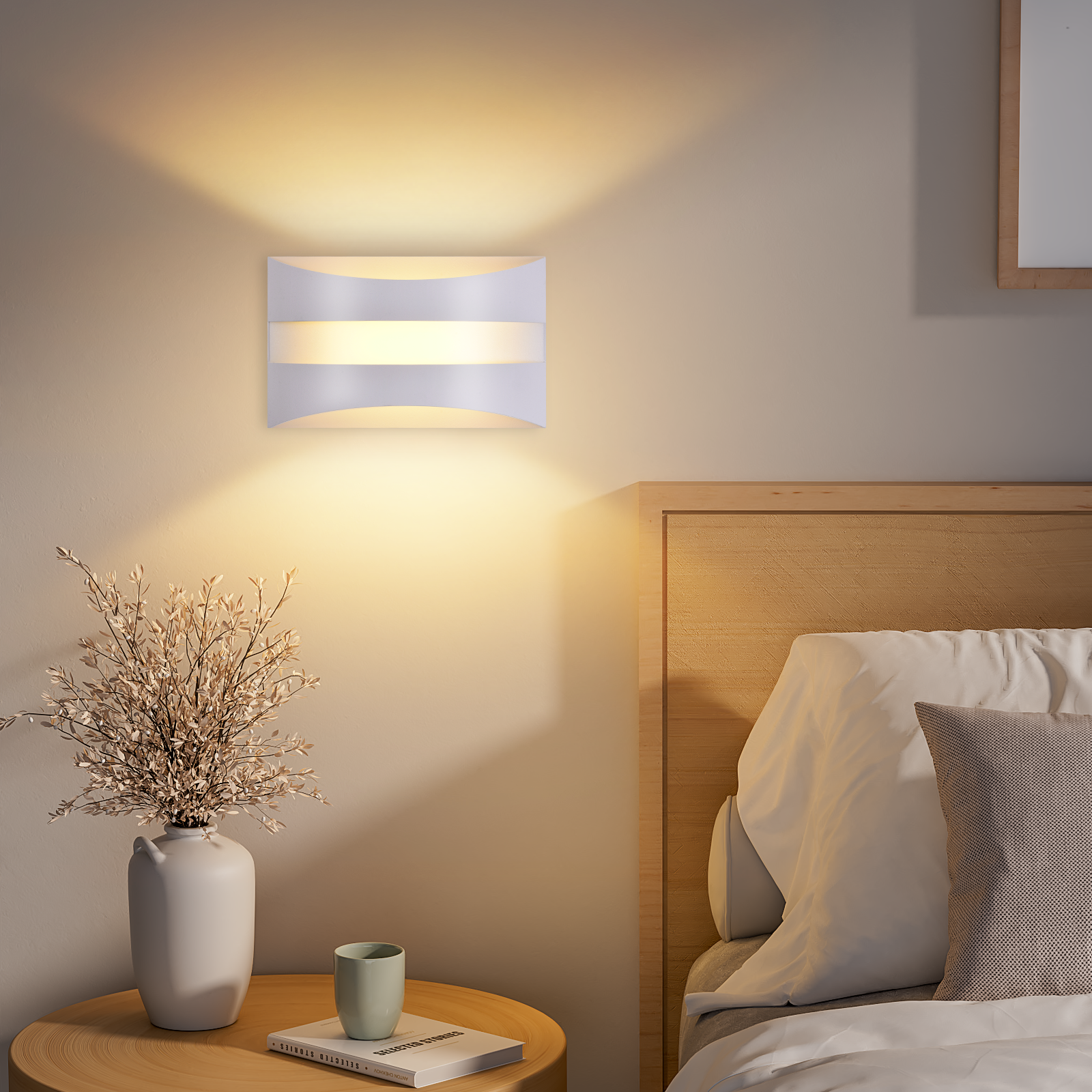Lámpara de pared sobre una cama de dormitorio con mesita de noche, florero y libro.