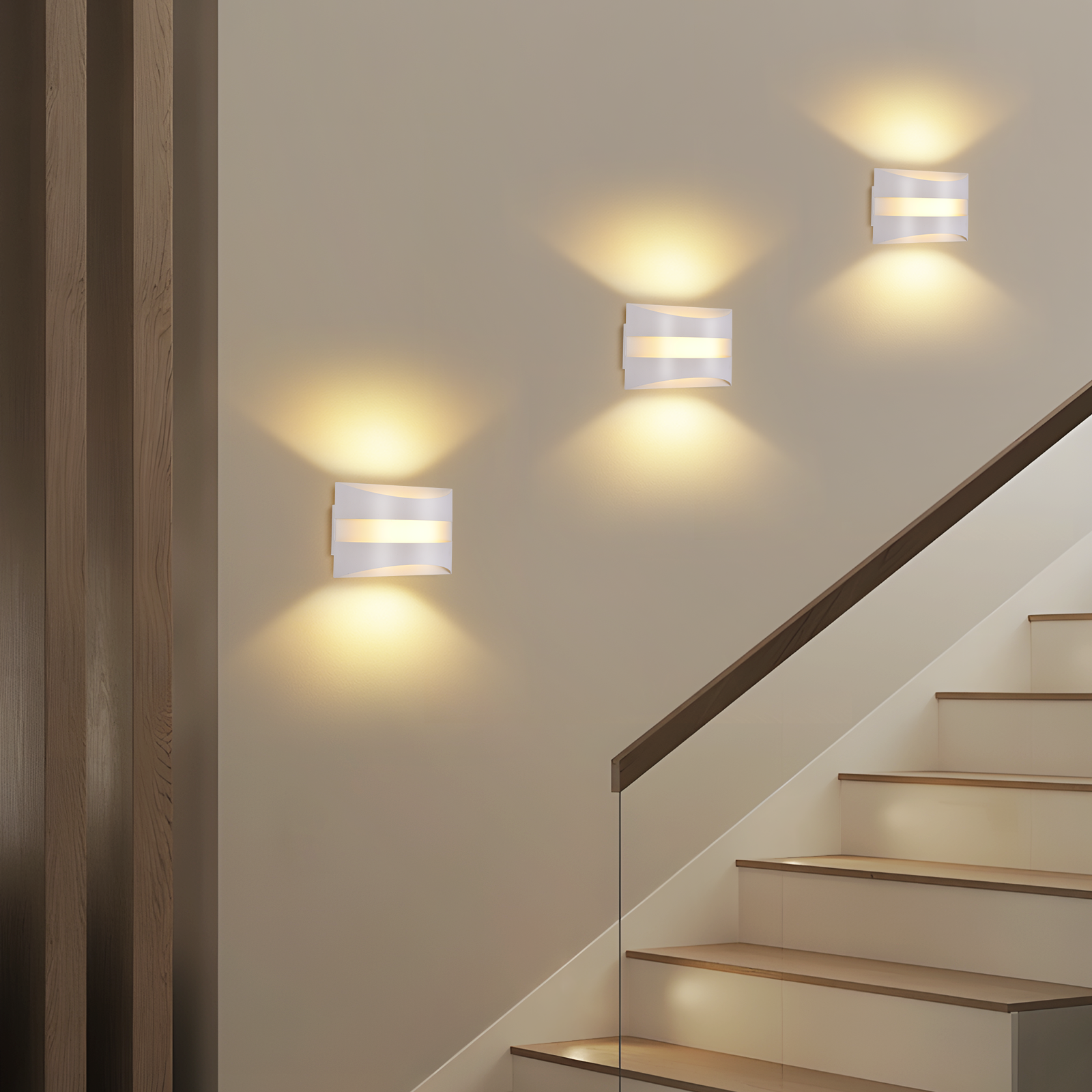 Tres modernos apliques blancos proyectan luz cálida en una pared beige junto a una escalera.