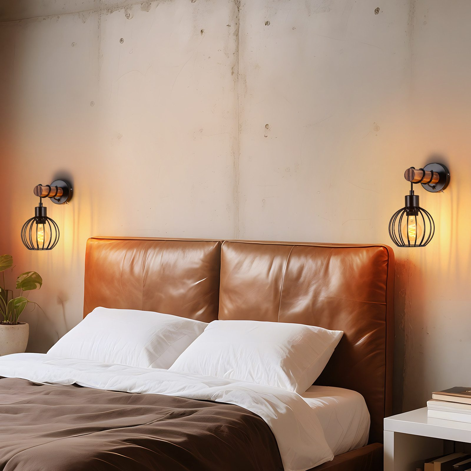 Una cama de cuero marrón con cojines blancos contra una pared, flanqueada por dos apliques negros.