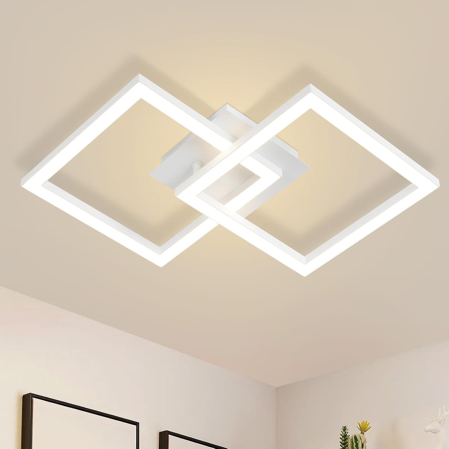 Una moderna lámpara de techo blanca con marcos cuadrados brillantes superpuestos en un techo liso.
