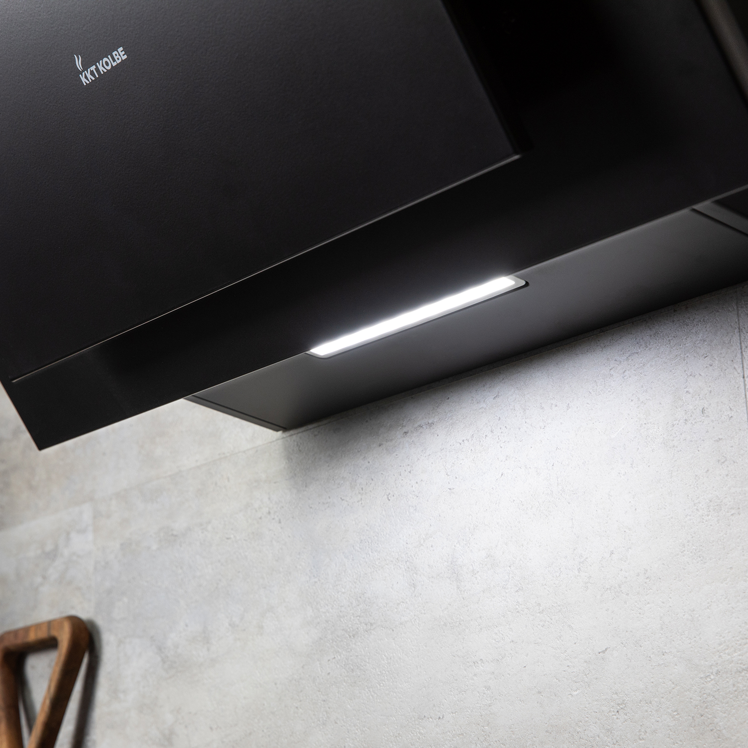 Una cappa da cucina nera con striscia LED illuminata su una parete grigio chiaro.
