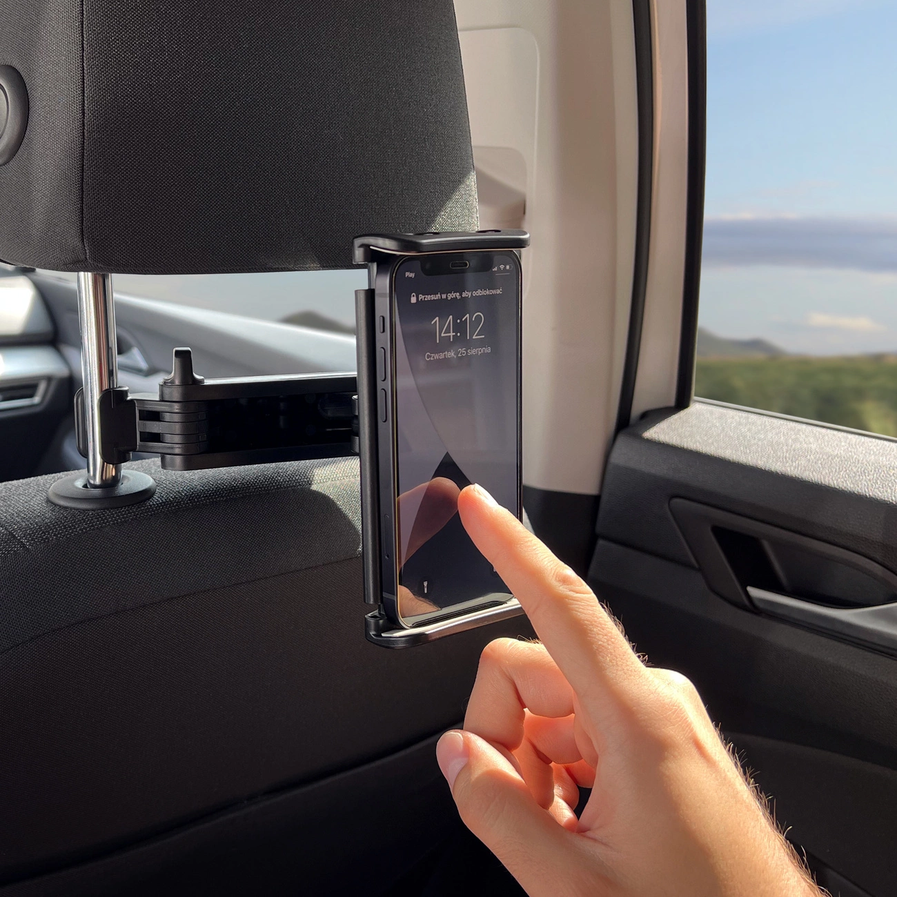 Una mano tocca uno smartphone montato su una staffa per poggiatesta di un'auto.