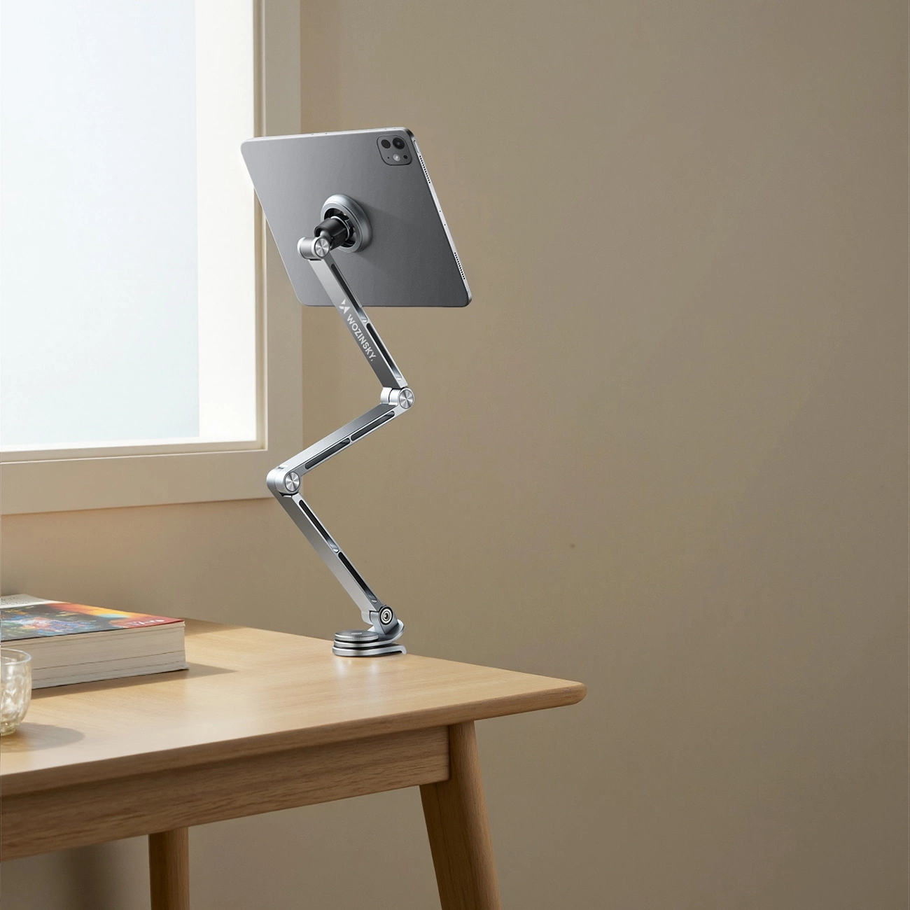 Un supporto per tablet argentato su una scrivania in legno sostiene un tablet grigio.