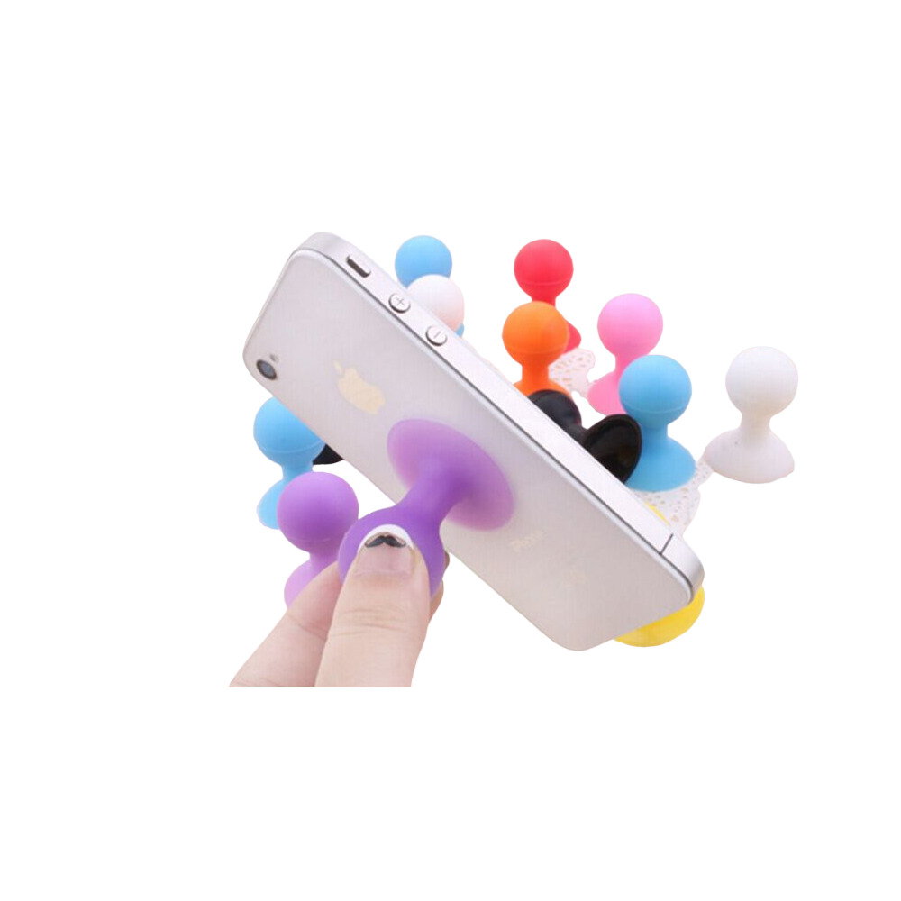 Mano che regge uno smartphone con un supporto a ventosa in silicone viola e altri supporti colorati sullo sfondo.
