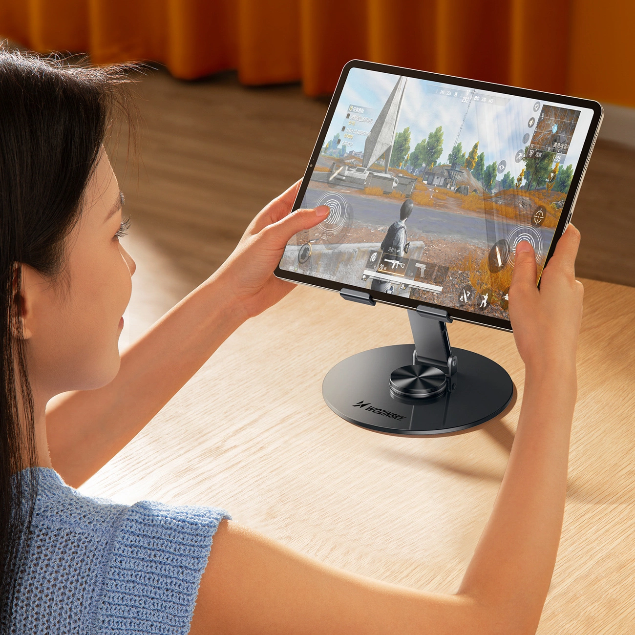 Una donna che gioca a un videogioco su un tablet montato su un supporto, su un tavolo di legno.