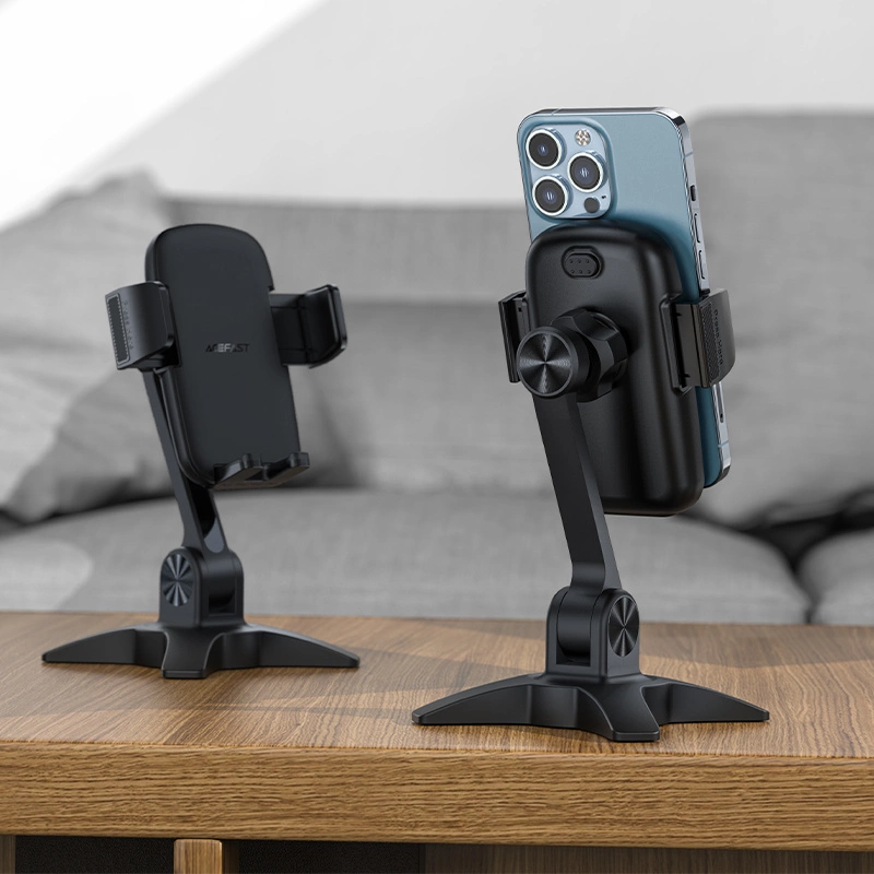 Due supporti per telefono neri con bracci regolabili su un tavolo di legno, uno sostiene uno smartphone.