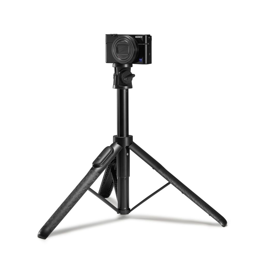 Una piccola fotocamera Sony nera montata su un treppiede nero su sfondo bianco.