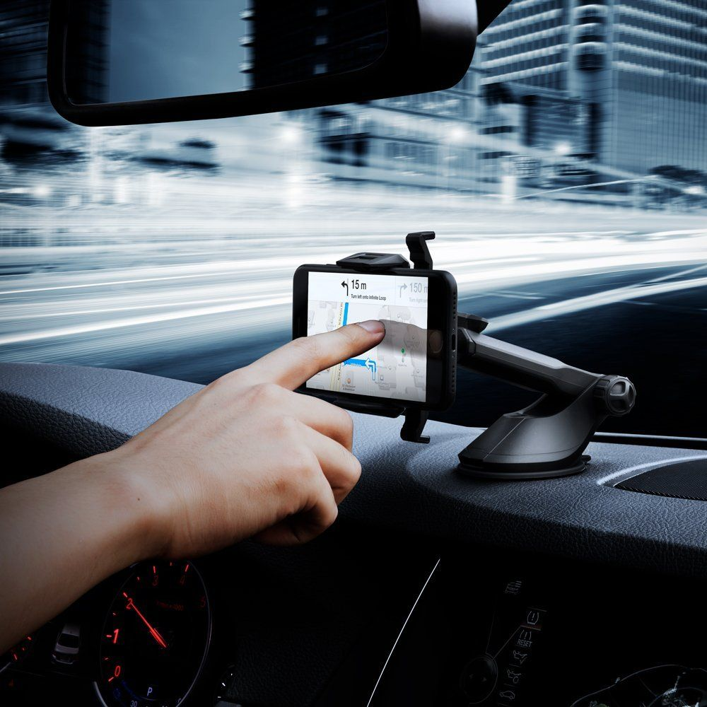 Una mano tocca uno smartphone sul cruscotto con una mappa di navigazione e traffico urbano sfocato.