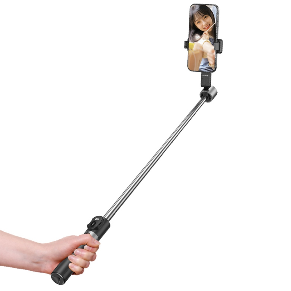 Una mano regge un selfie stick nero e argento esteso con uno smartphone che mostra una donna sorridente.