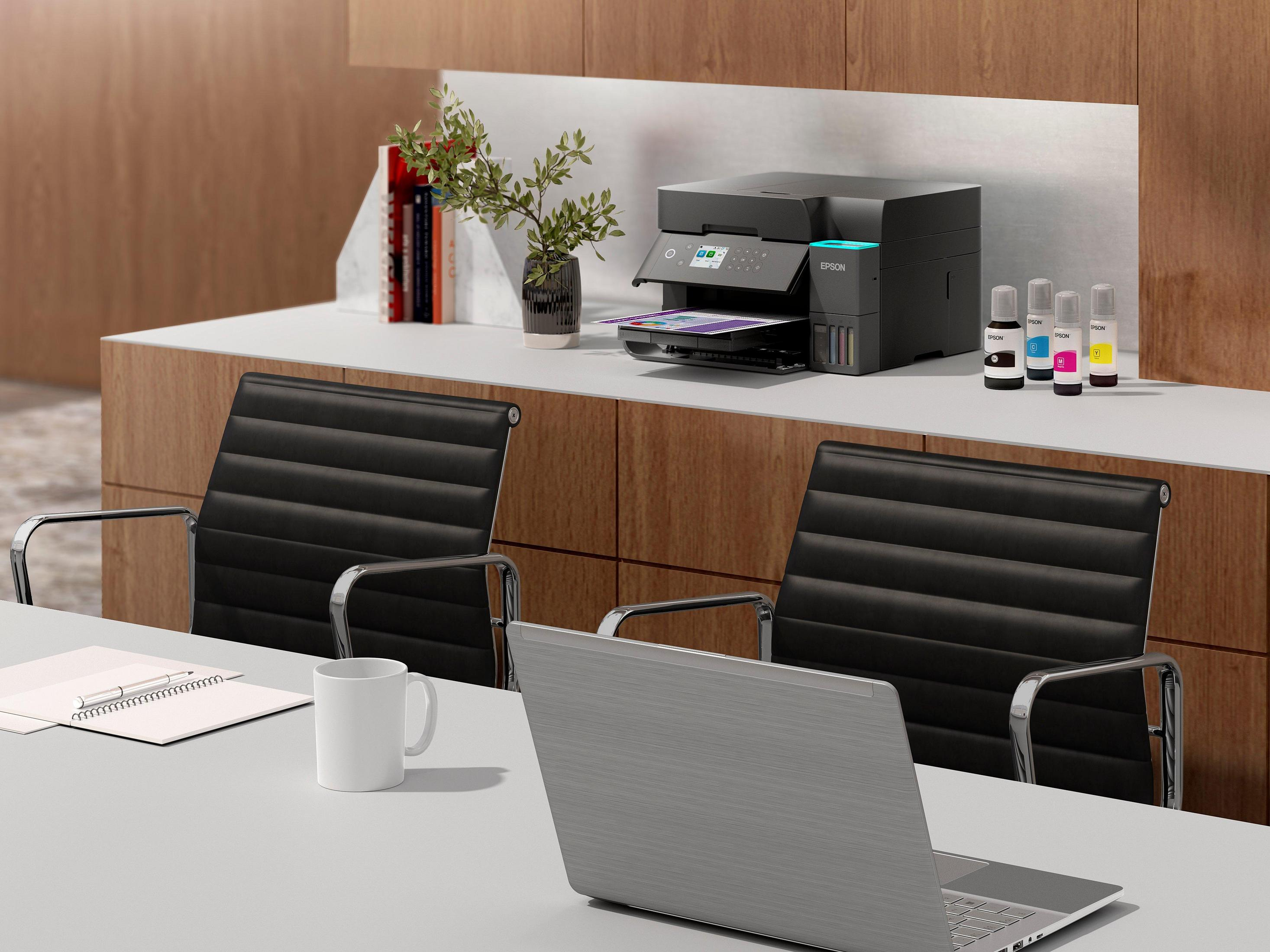 Yazıcı, dizüstü bilgisayar, beyaz kupa ve iki siyah sandalyeli modern ofis sahnesi.