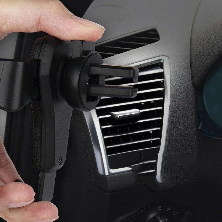 Una mano fissa un supporto nero per auto alla bocchetta d'aerazione del cruscotto.