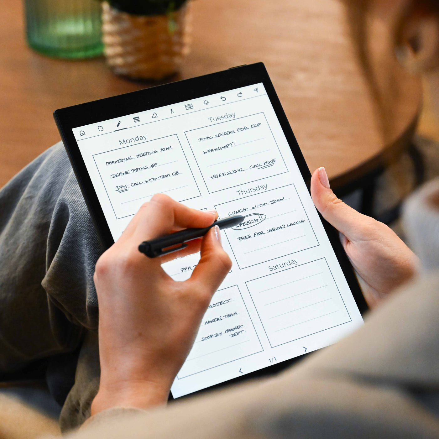 Una persona escribe con un lápiz óptico en una tablet con un calendario semanal.