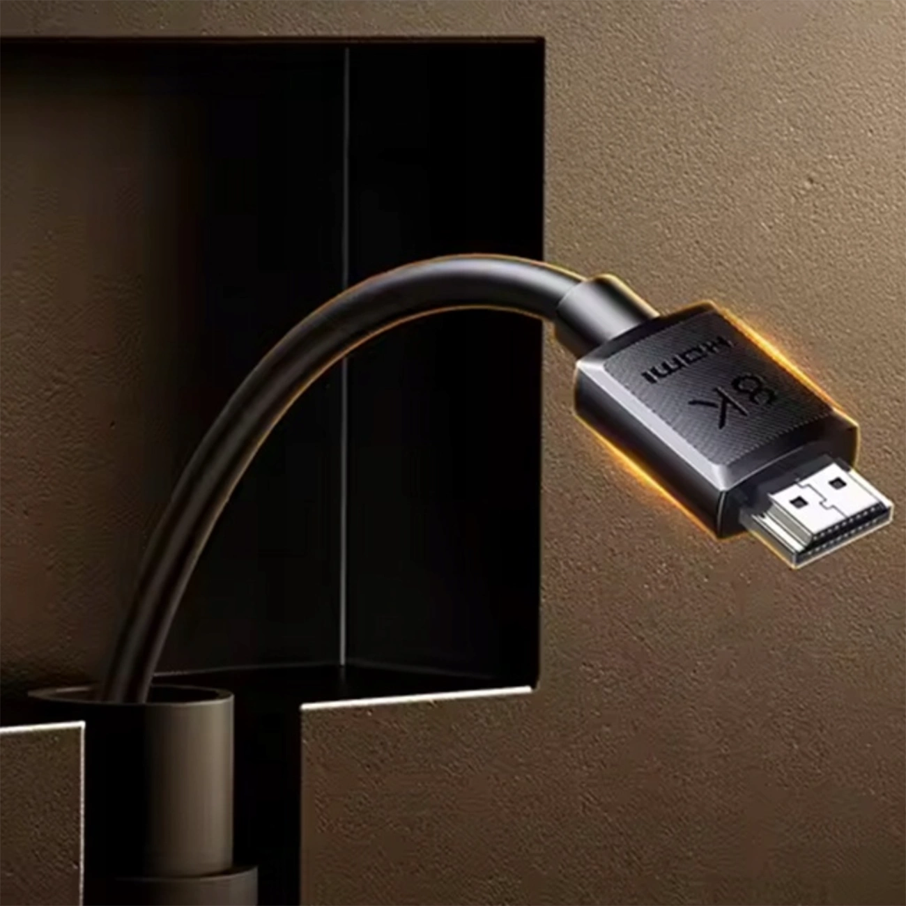 Un cavo HDMI 8K nero fuoriesce da una fessura in una parete scura e testurizzata, illuminandosi debolmente.