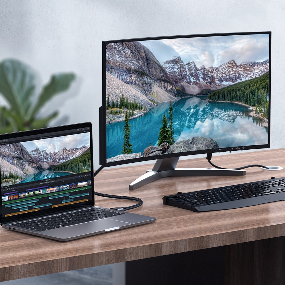 Un laptop è collegato via cavo a un grande monitor, entrambi mostrano un paesaggio montano.