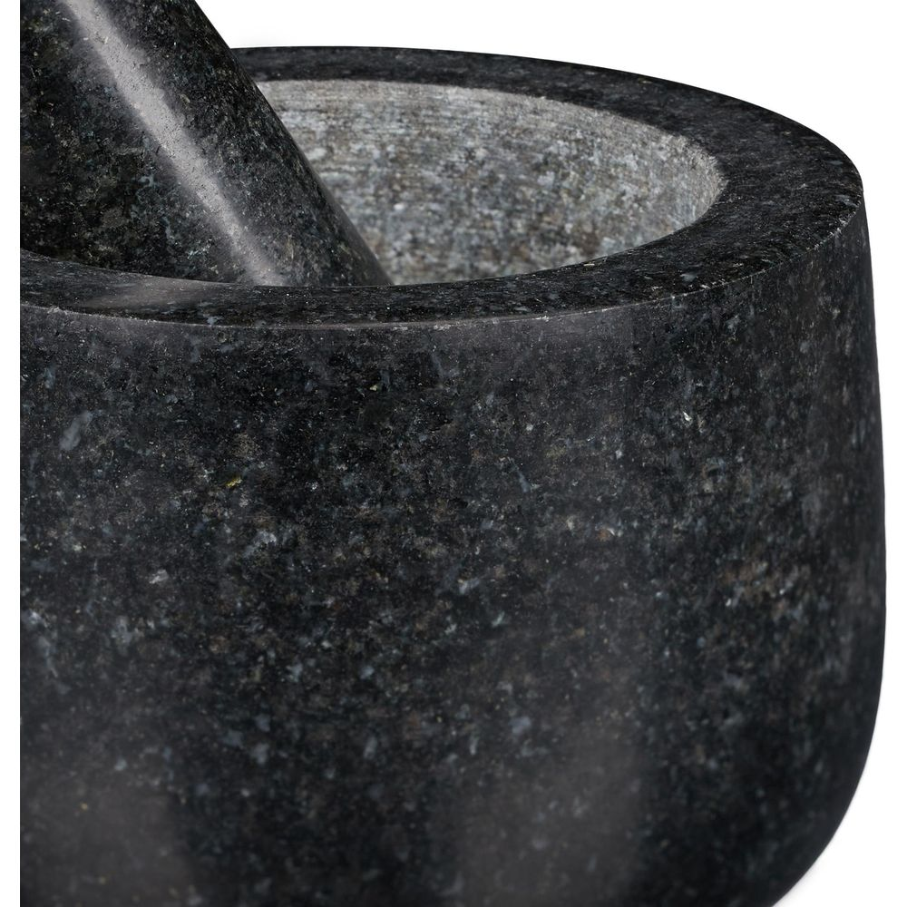 Nahaufnahme eines dunkelgrauen Granitmörsers mit Stößel vor weißem Hintergrund.