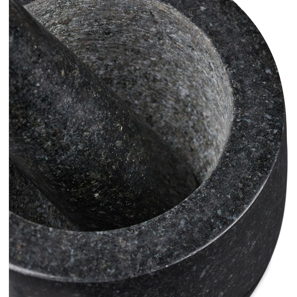 Ein schwarzer Granitmörser mit passendem Stößel steht auf weißem Grund.
